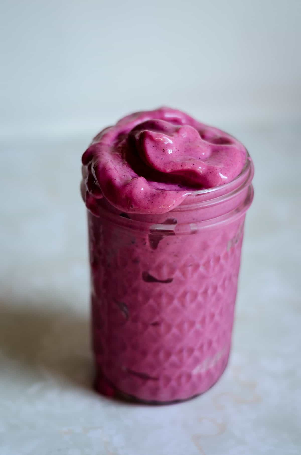 Pink thick smoothie in a jar on the counter ready for breakfast.