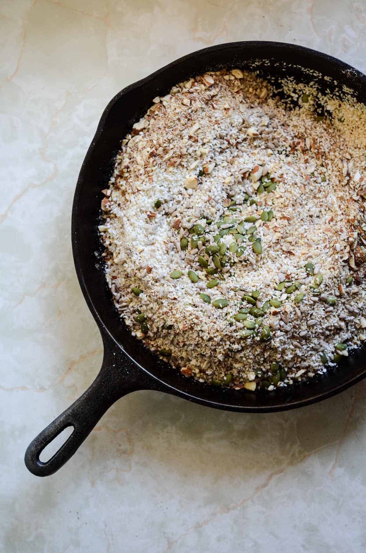 Fry pan with coconut, almonds, flax seeds, sunflower seeds, to toast.
