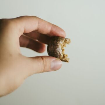 Hand holding protein ball with a bite missing.