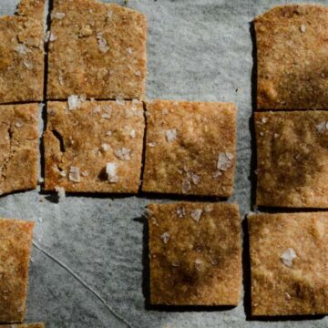Crackers similar to wheat thins on a baking pan with sea salt.