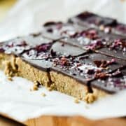 No bake almond butter protein bars with chocolate on top on platter.