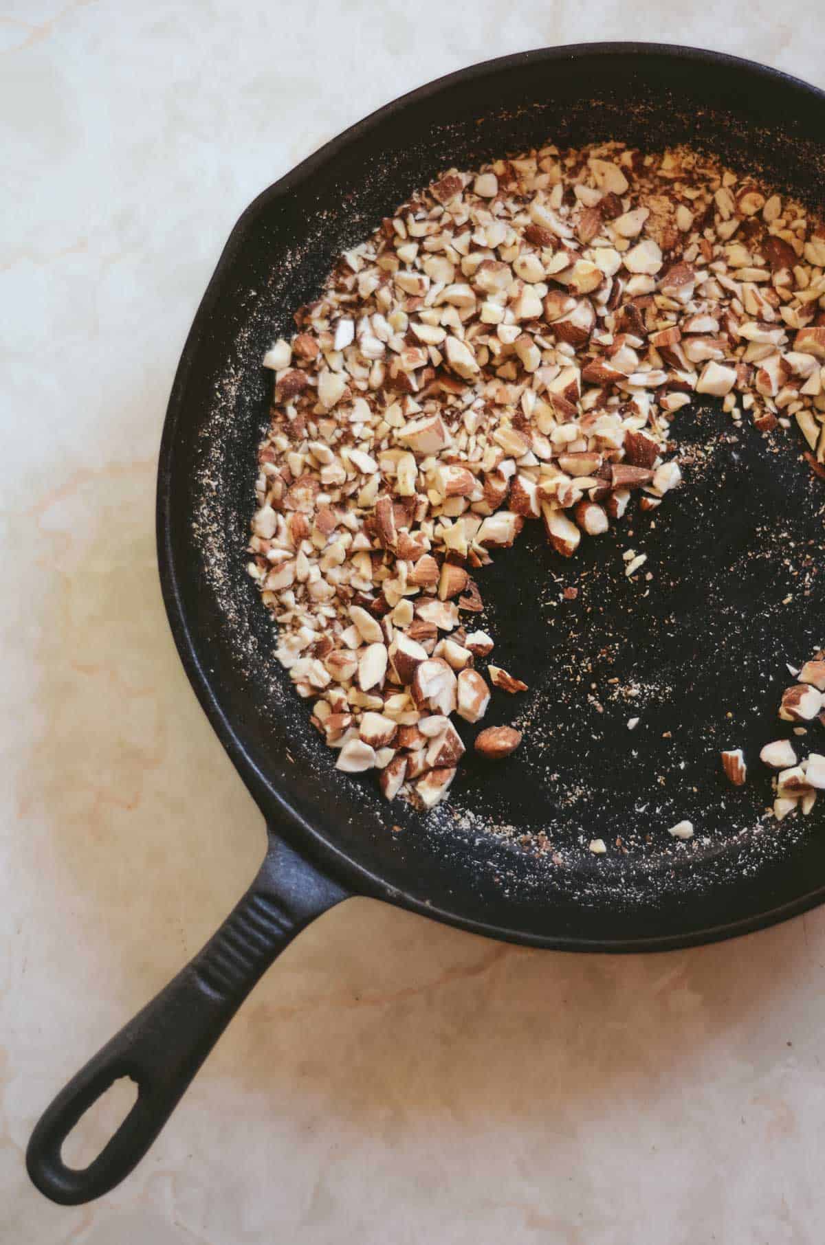 Chopped almonds in a cast iron fry pan.