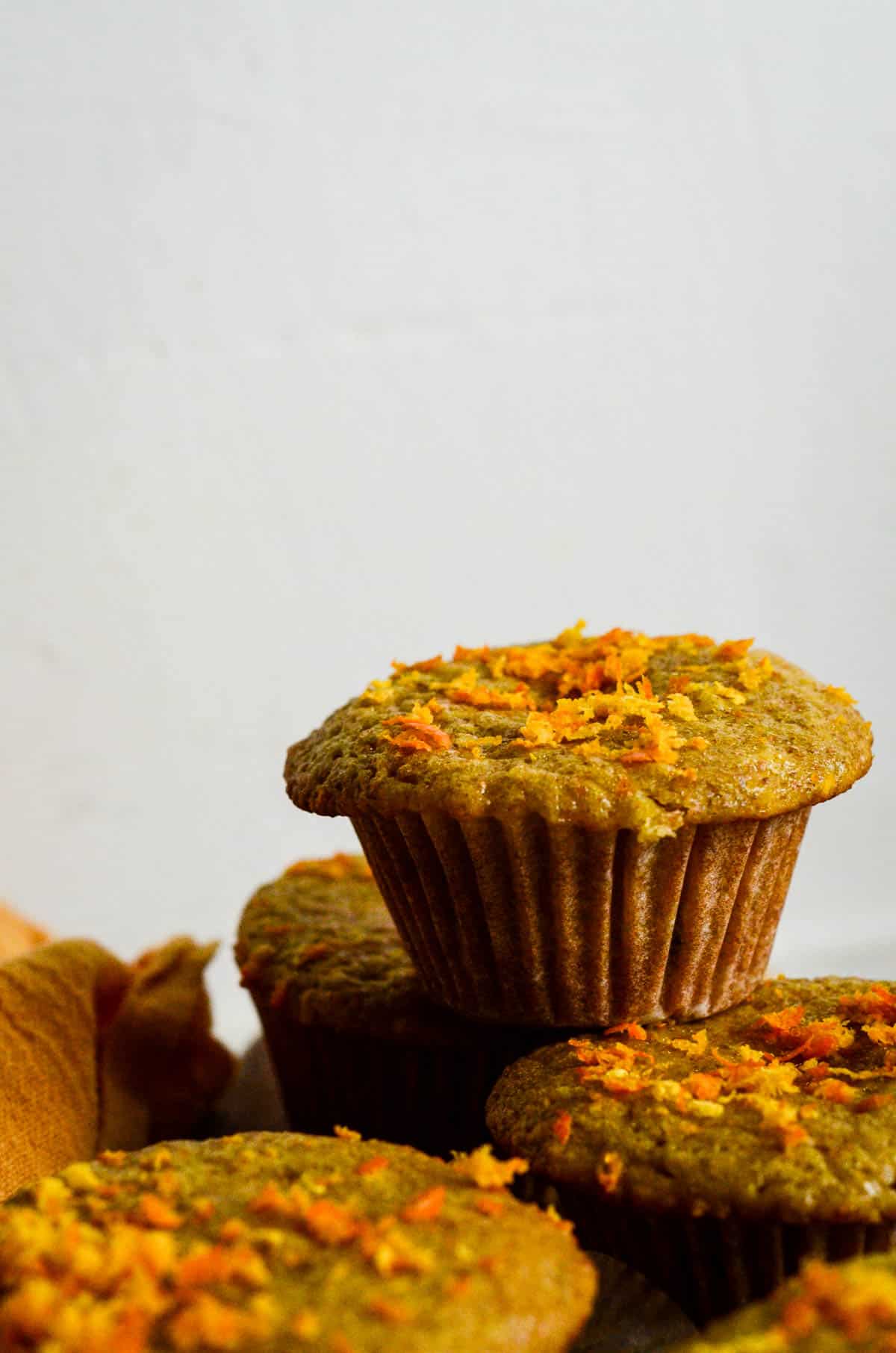 Orange colored muffin with zest flecks on top. 