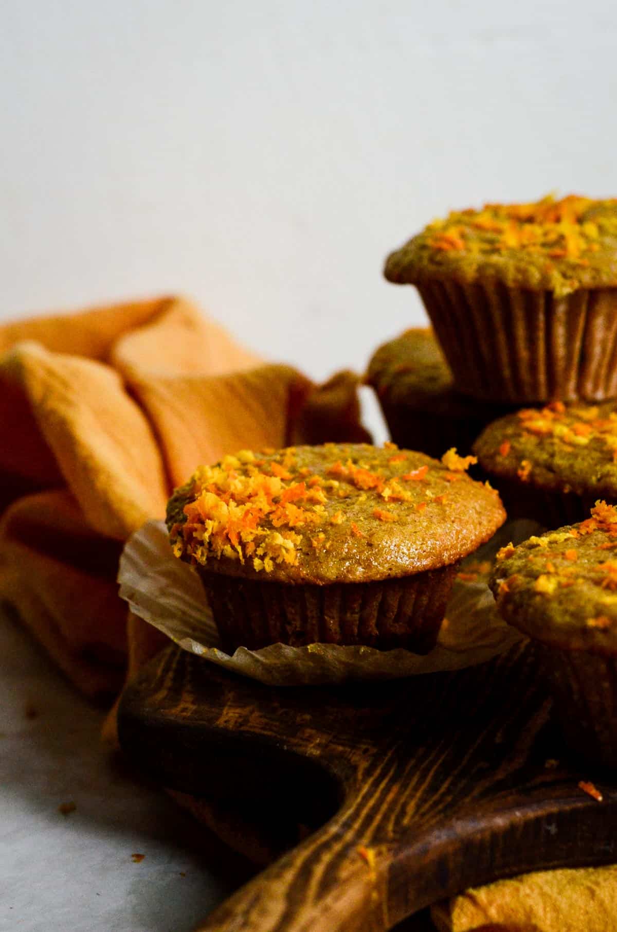 Orange colored muffin with zest flecks on top. 