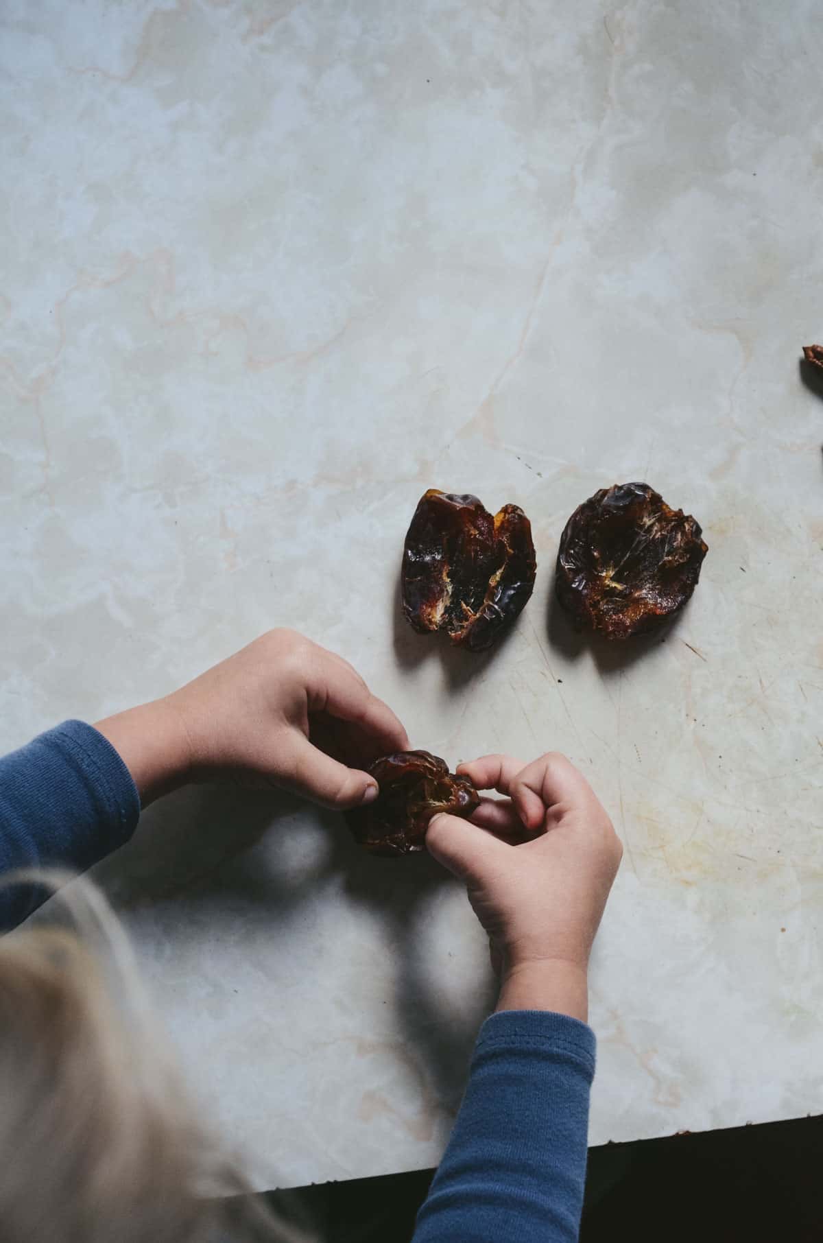 Toddlers hands removing pit from dates.