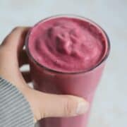 Hand holding pink smoothie cup.