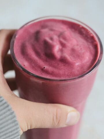 Hand holding pink smoothie cup.