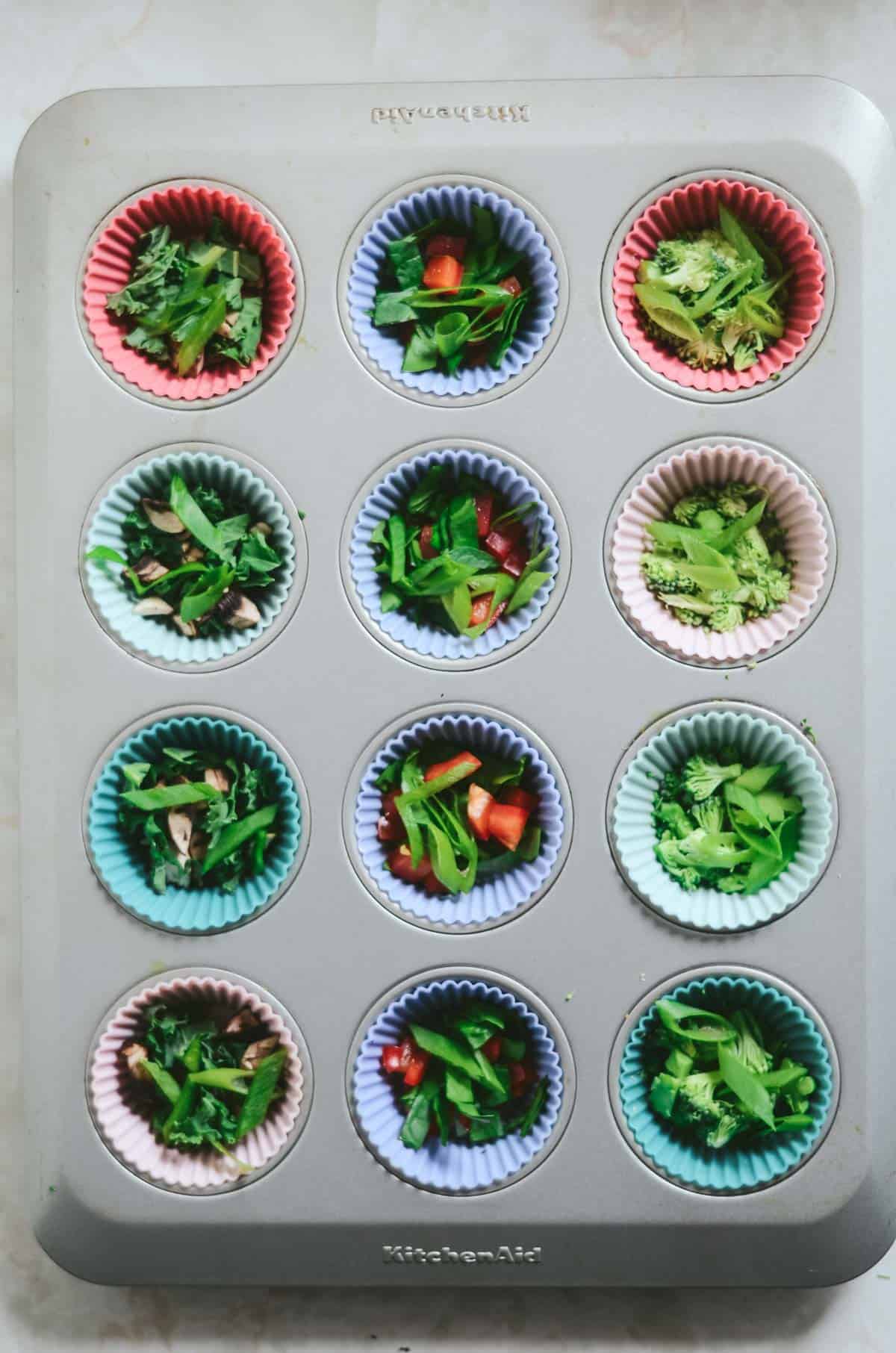 Veggies in silicone liners in a muffin tray. 