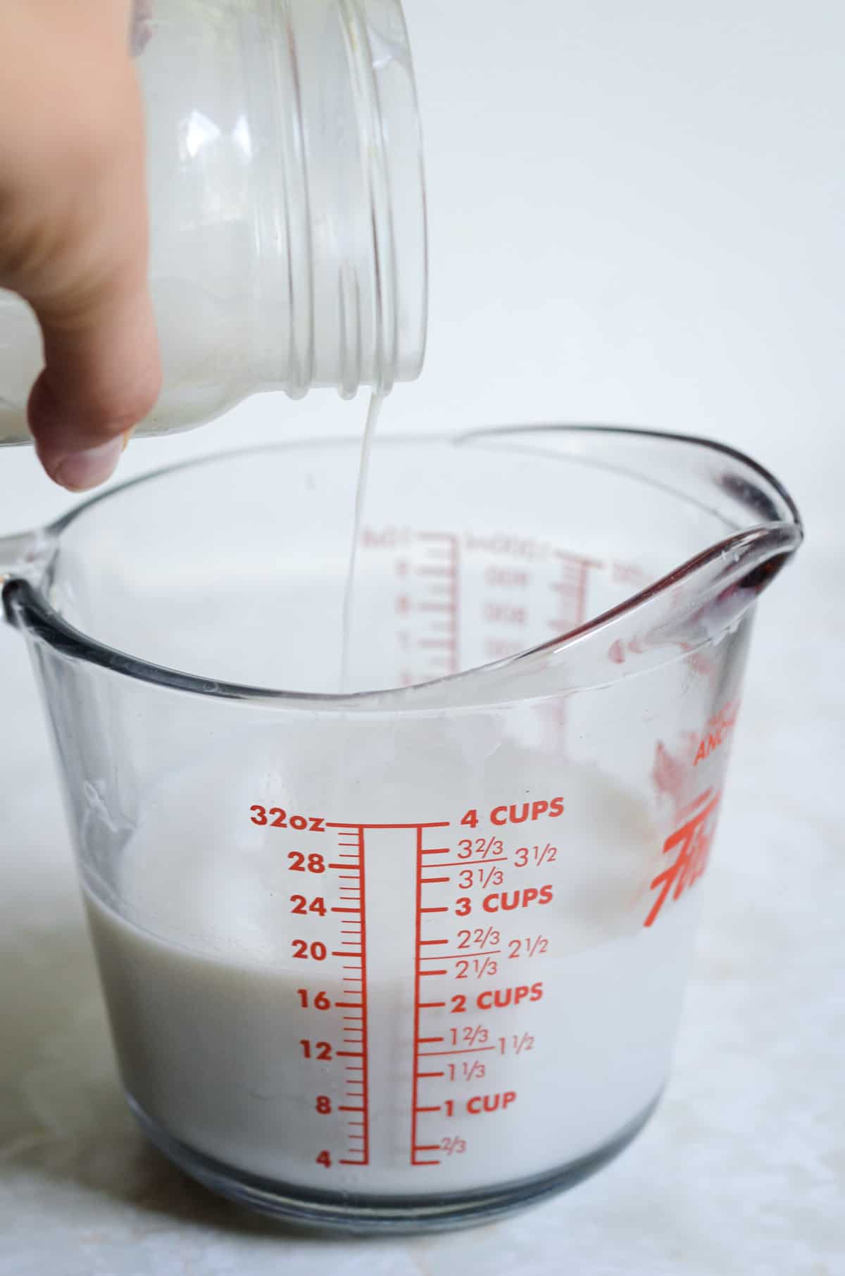 Glass measuring cup pouring milk into it.
