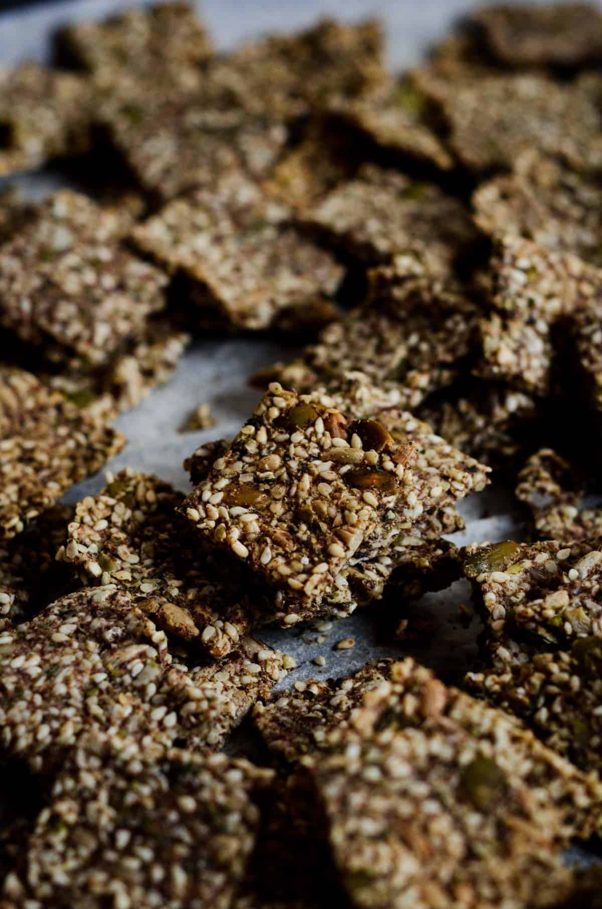 Square seed crackers scattered on a cookie sheet.