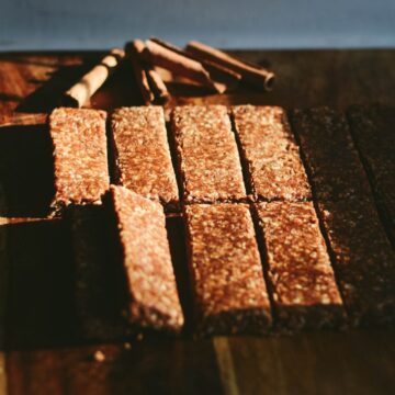 12 oatmeal bars bars on a cutting board cut into 12 bars with cinnamon stick behind.