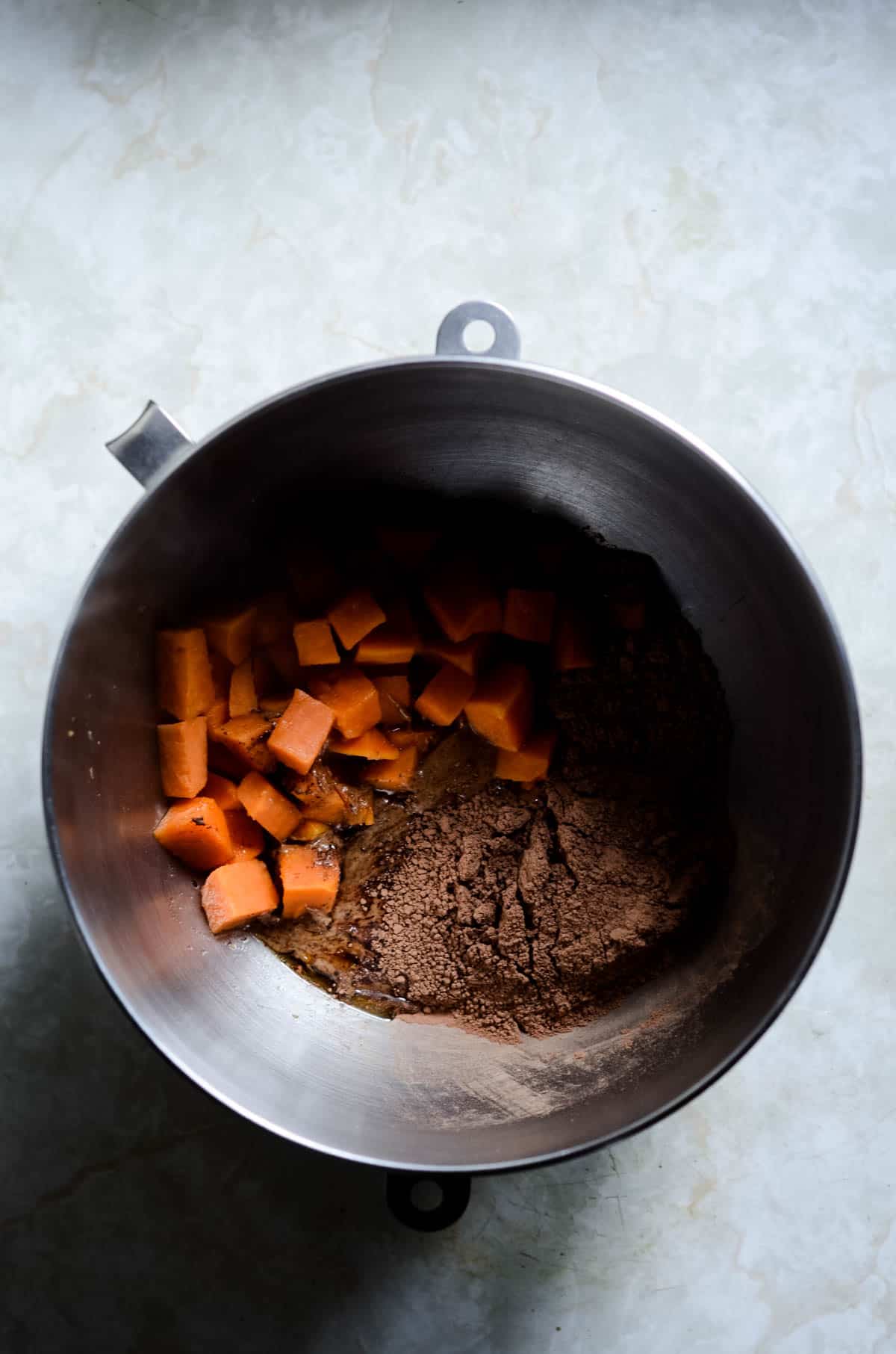 Sweet potato, cocoa powder, maple syrup, and almond butter in a kitchen aid mixing bowl.