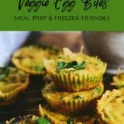 Bright yellow egg bites with spinach and kale veggie flecks in them, stacked on serving board.