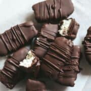 Bounty bars with fresh chocolate covering the coconut on parchment paper.