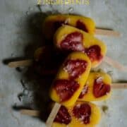 Strawberry mango popsicles stacked on top of each other.