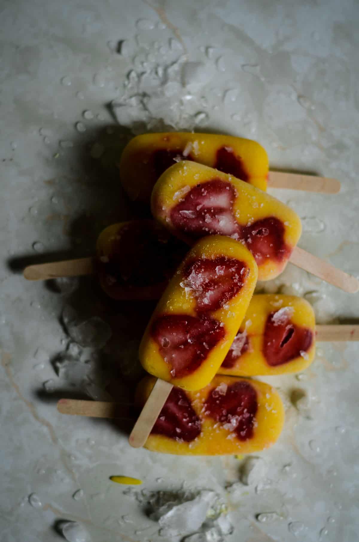 Mango popsicles with strawberry chunks.