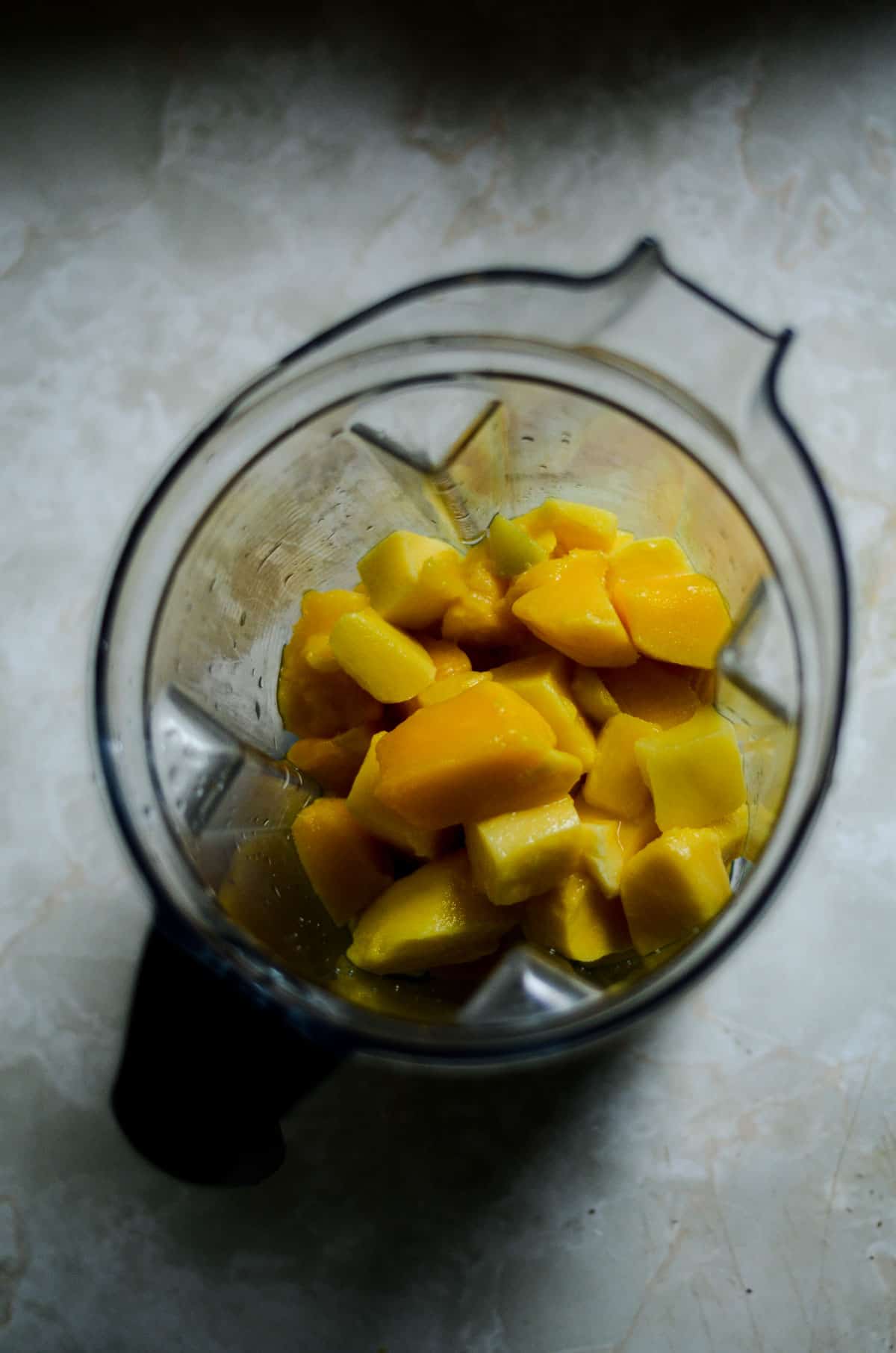 Mango chunks in a vitamix ready to be blended.