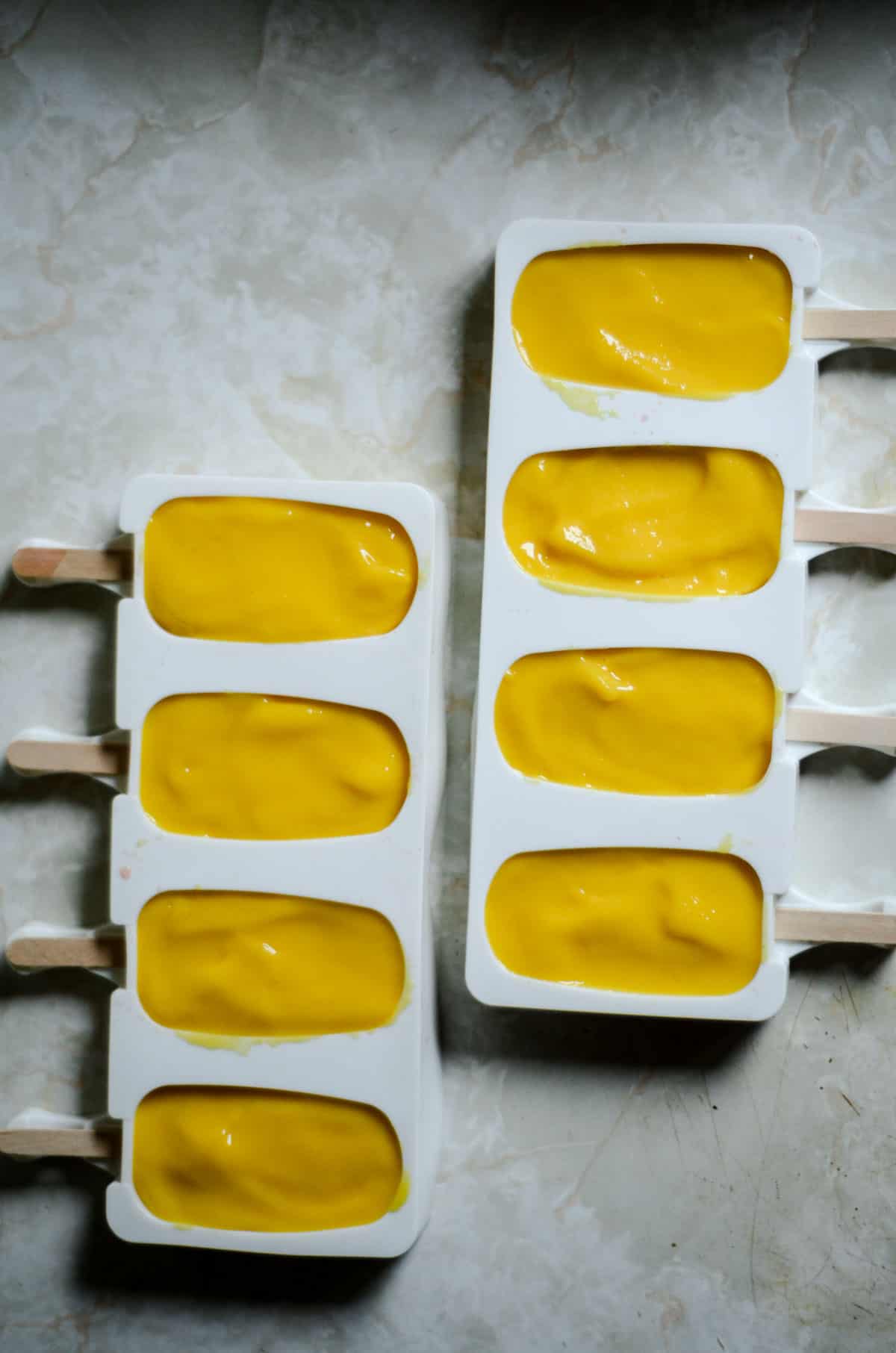 Silicone popsicle mold filled with mango puree.