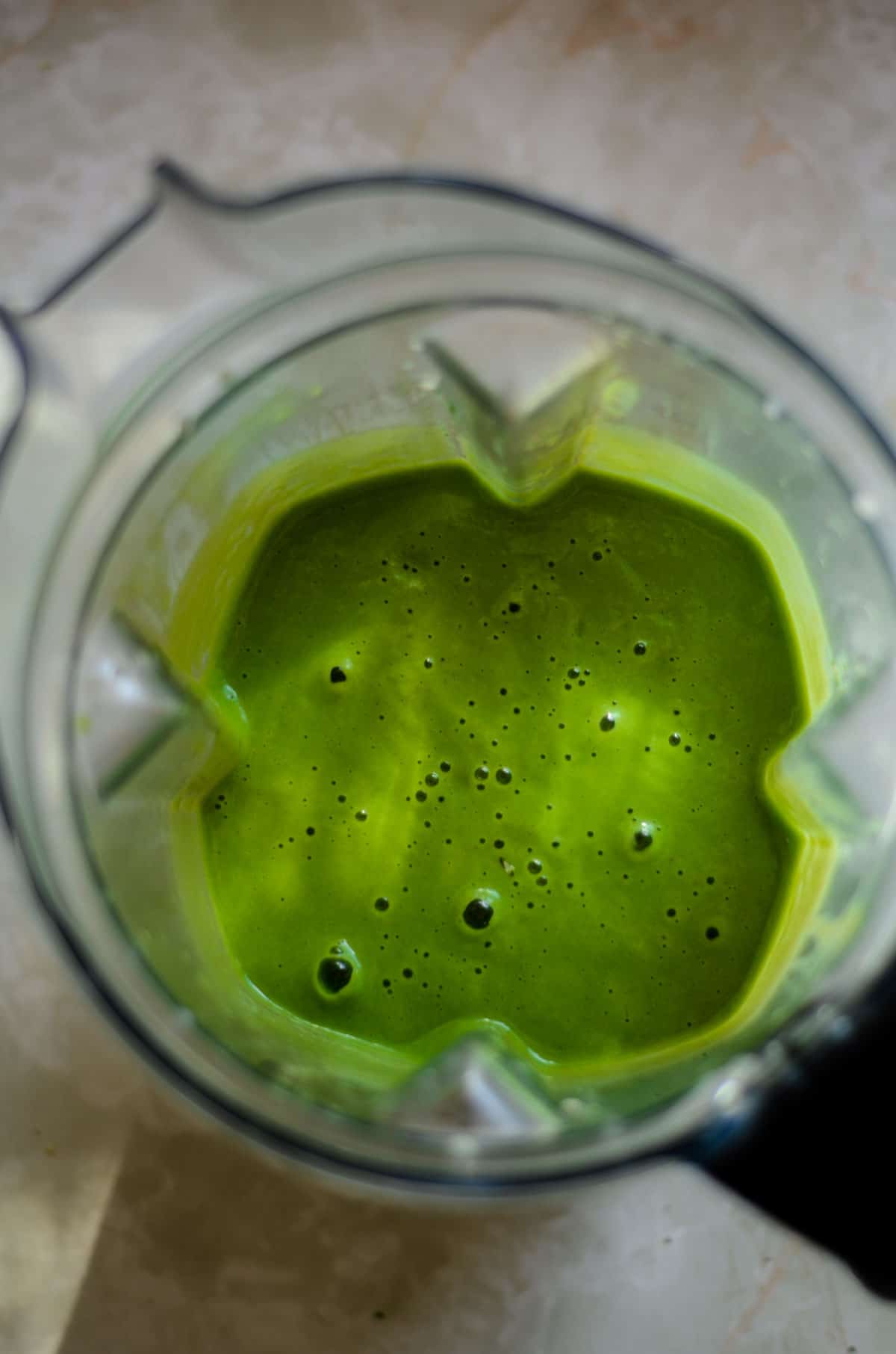 Smooth green spinach fruit smoothie in a blender container.