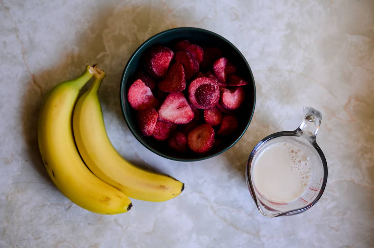 Ingredients for an easy strawberry smoothie without yogurt, bananas, strawberries, almond milk.