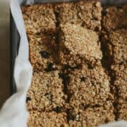 Chewy honey flapjacks cut into bars in a 8x8 pan which parchment paper.