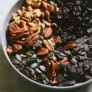 Dark chocolate, pumpkin seeds, walnuts, pecans, dried cherries, in a bowl.