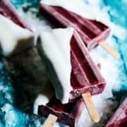 Healthy frozen cherry popsicles with yogurt and honey sitting on ice.