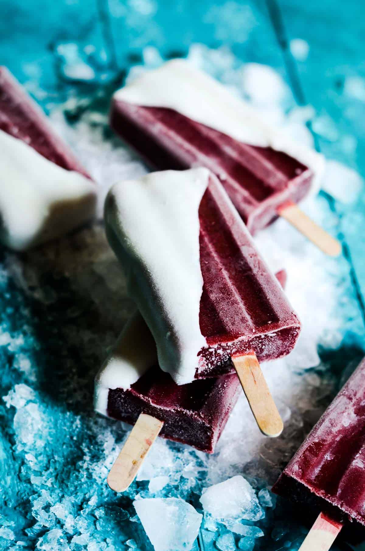 Close up of a dark red sweet cherry popsicle dipped in white yogurt.