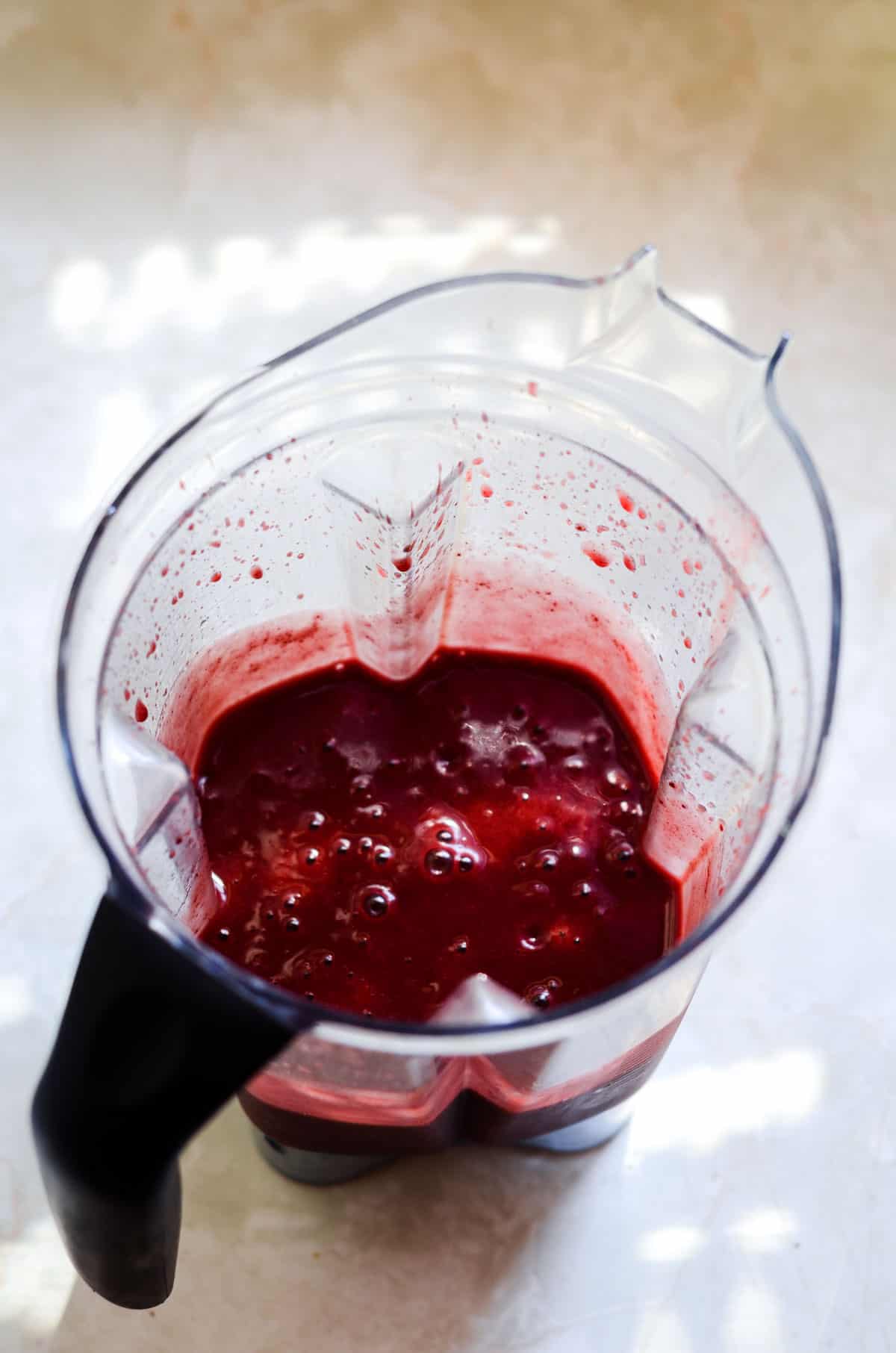 Dark red cherry liquid in a blender container for healthy popsicles.