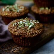 Close side angle of a brown zucchini bran muffin on a wooden platter.