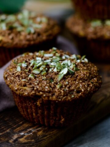 Close side angle of a brown zucchini bran muffin on a wooden platter.