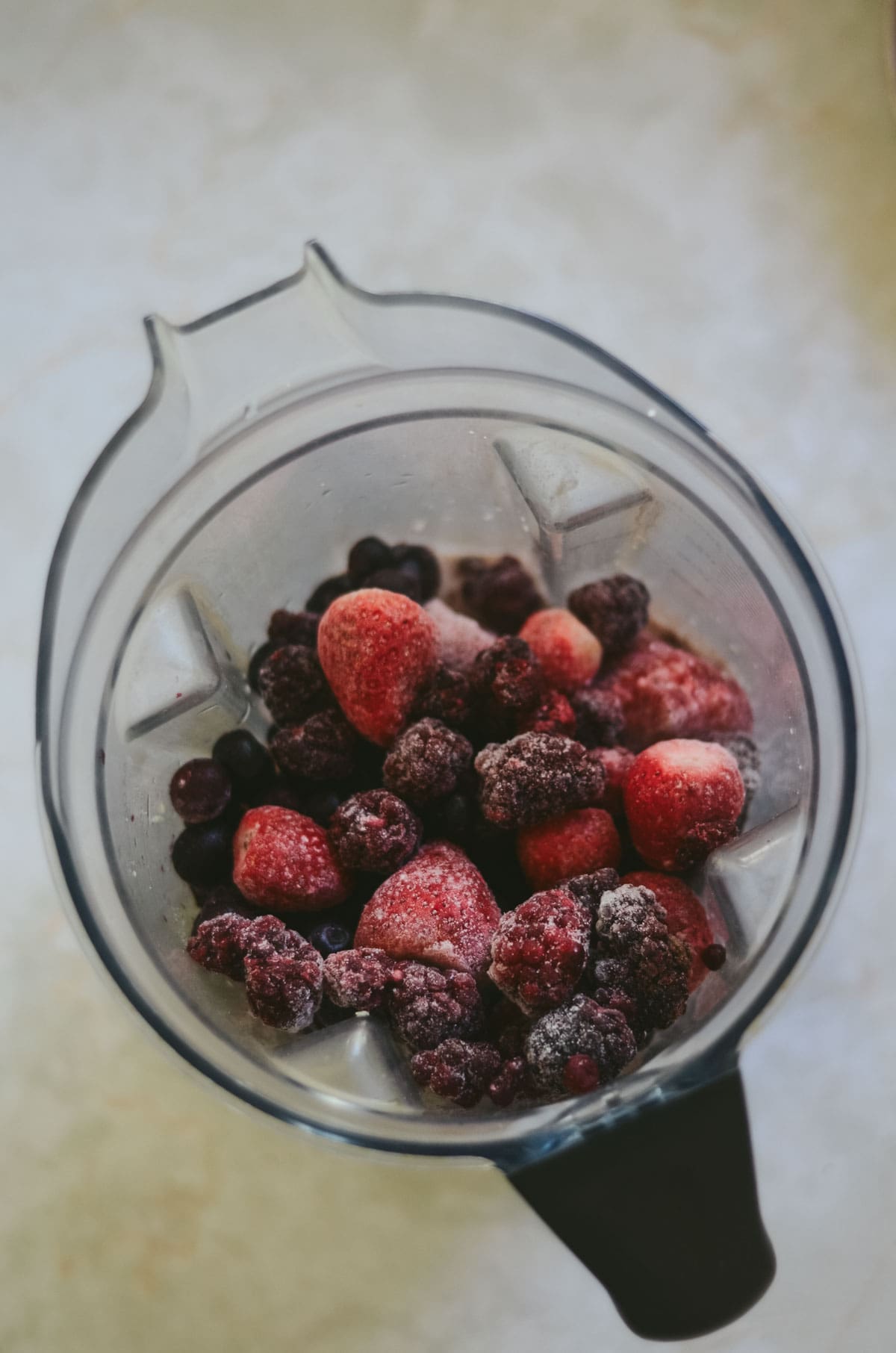 Frozen mixed berries, blueberries, strawberries, blackberries, in the blender for a berry chocolate smoothie.