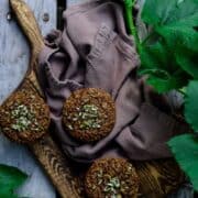 Zucchini Bran Muffins on a wooden serving board surrounded by green zucchini leaves of the plant.