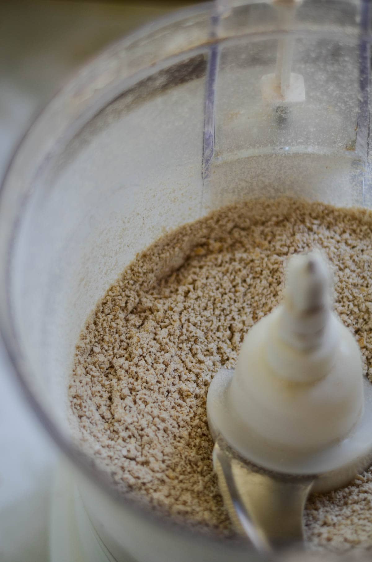 Blended oats in a food processor making oat flour.
