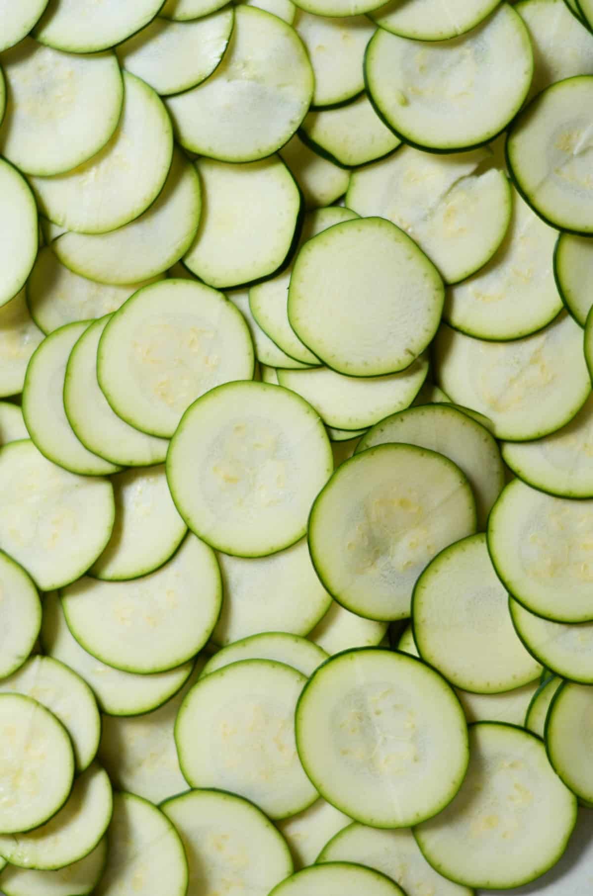 Green and white sliced zucchini round overlaying each other.