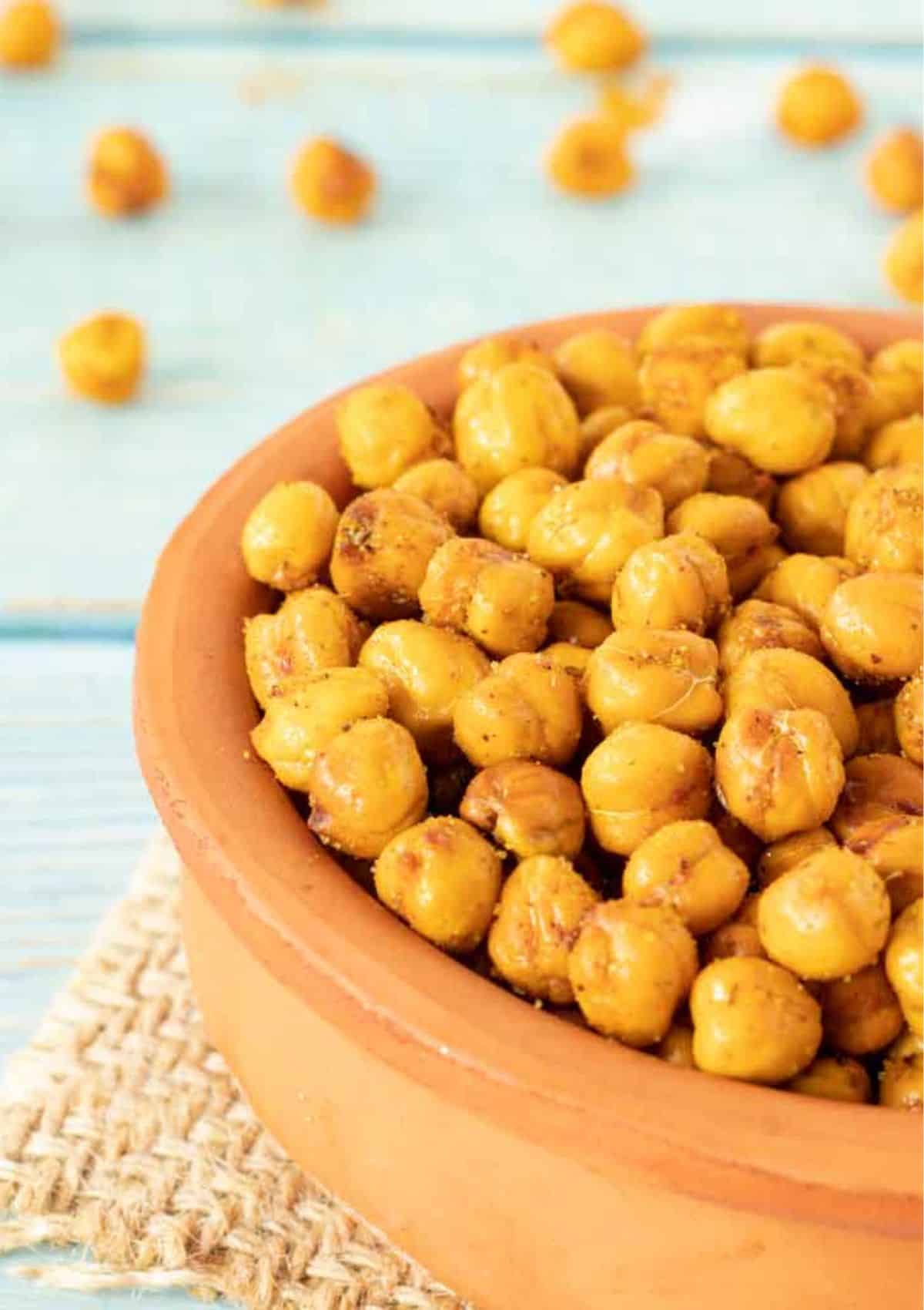 Light yellow colored chickpeas with spices on top in a brown bowl.