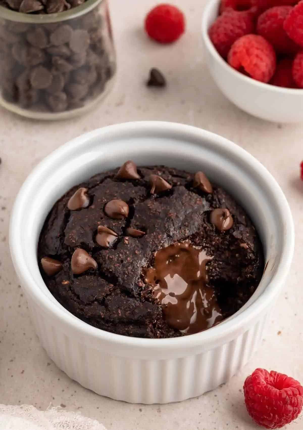 Chocolate cake with melted chocolate chips in a white little bowl.