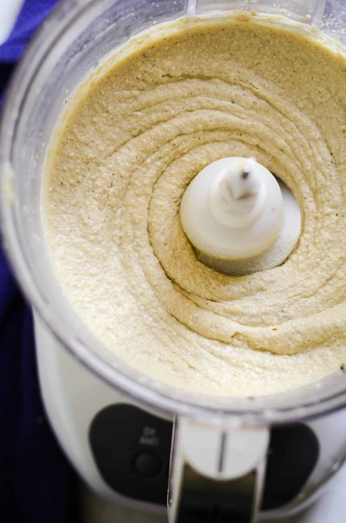 Super smooth homemade hummus in a food processor container.