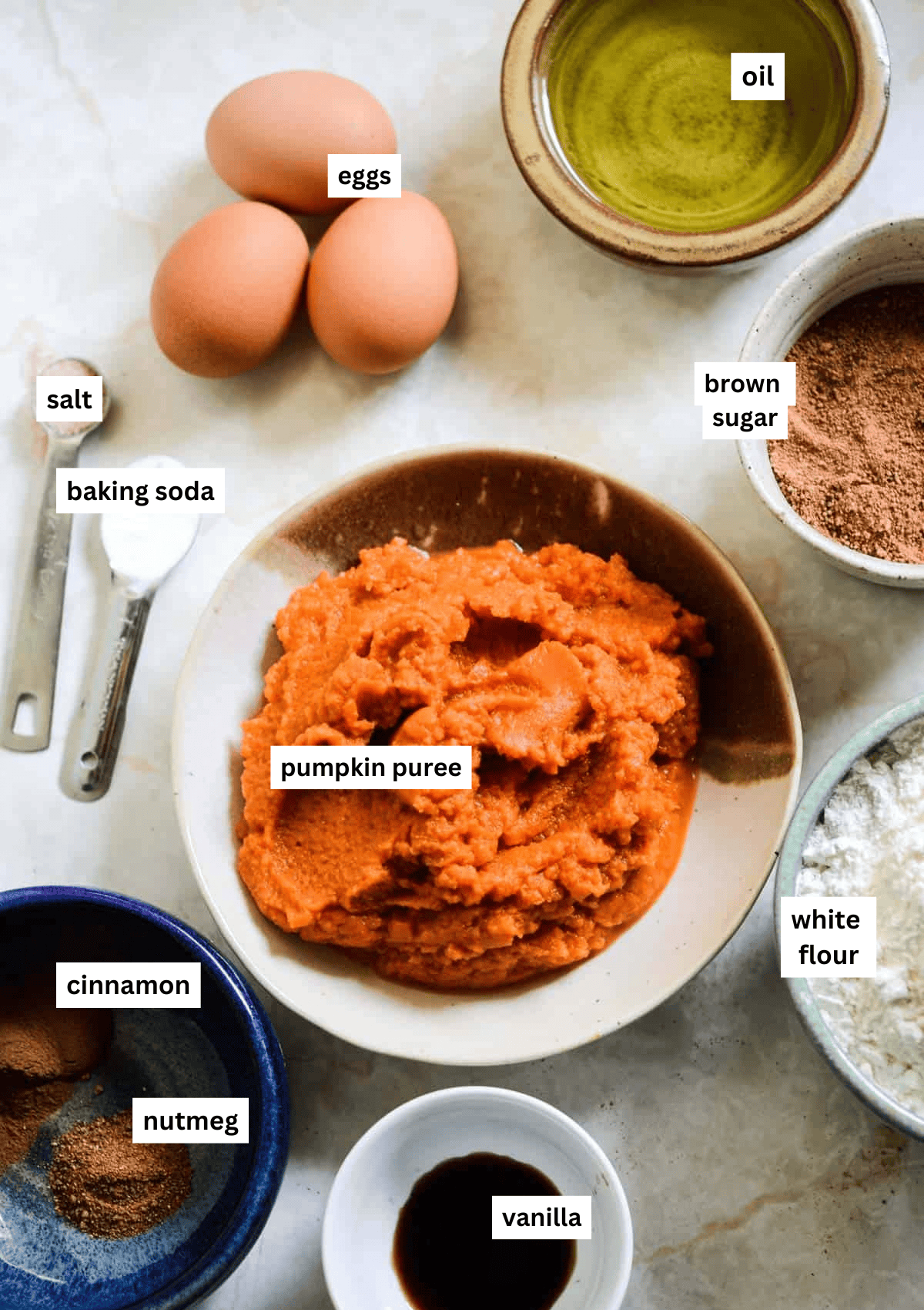 Pumpkin puree, eggs, oil, brown sugar, flour, vanilla, cinnamon, nutmeg, baking soda, salt, in bowls ready to make a snack cake.
