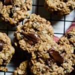 Oatmeal chocolate chip and raisin cookies cooling on a cookie rack with melted chocoalate.