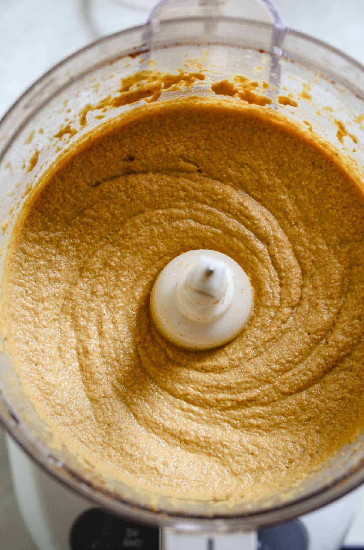 Smooth dairy free pumpkin cheesecake filling in food processor container. 