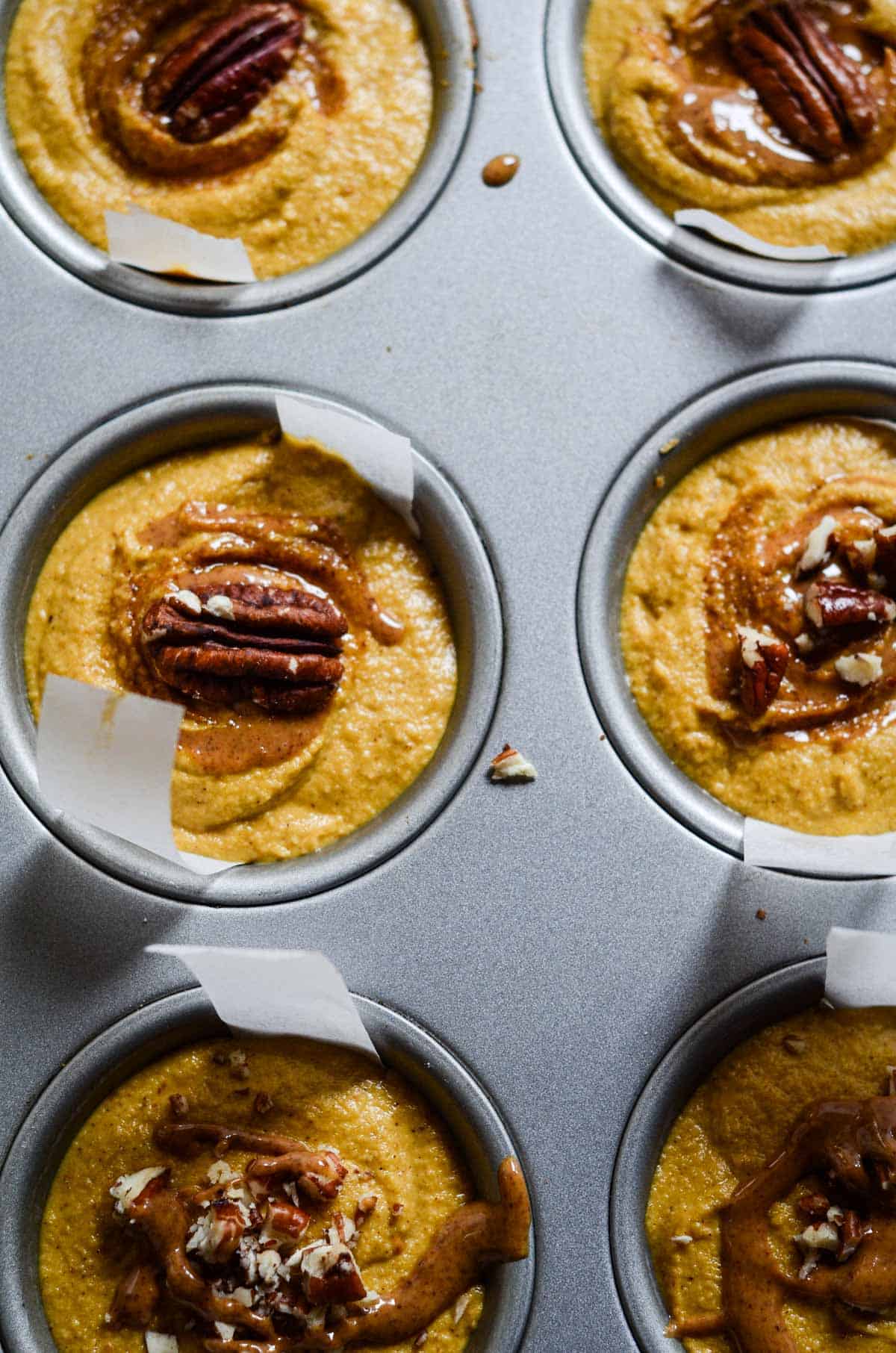 Dairy free cheesecake batter made from cashews in muffin tin with pecans on top.