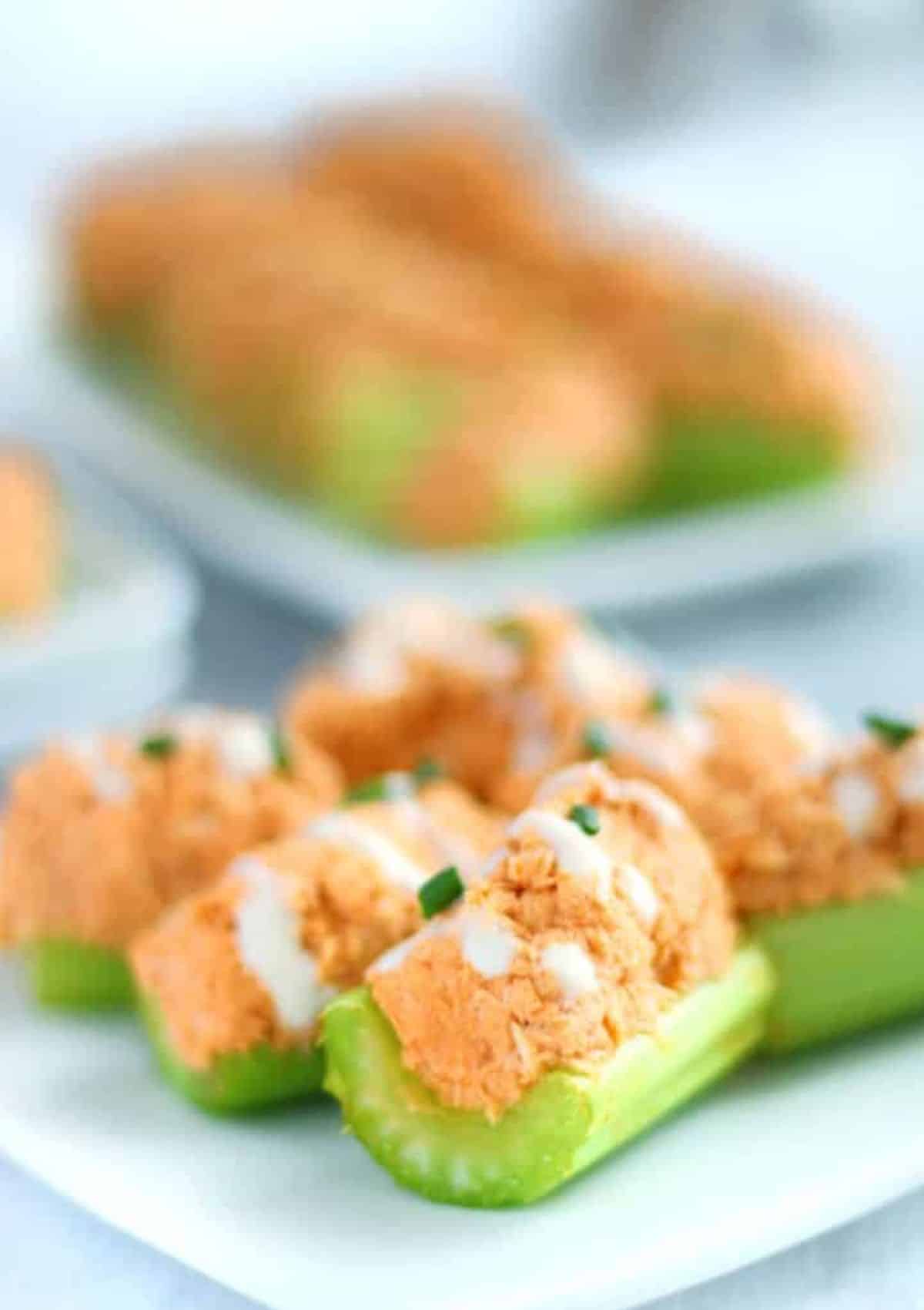 Orange colored tuna in celery sticks with ranch and chives on top)