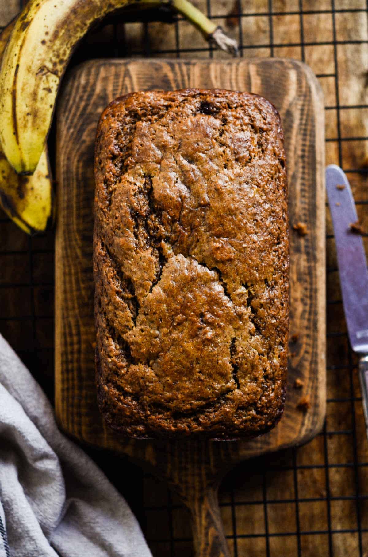 Fully baked moist golden brown banana bread with cracks on the top.