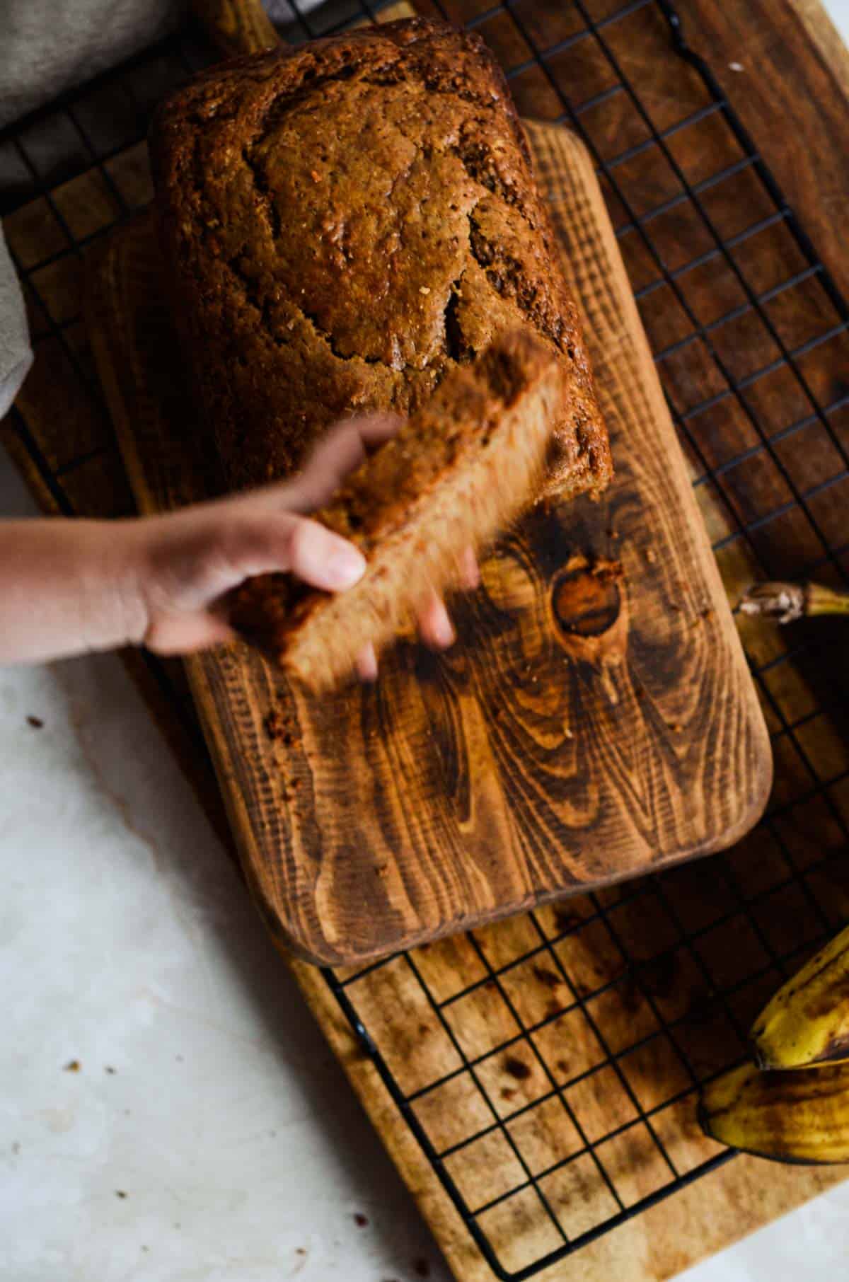 A piece of banana bread being grabbed by a toddler hand.