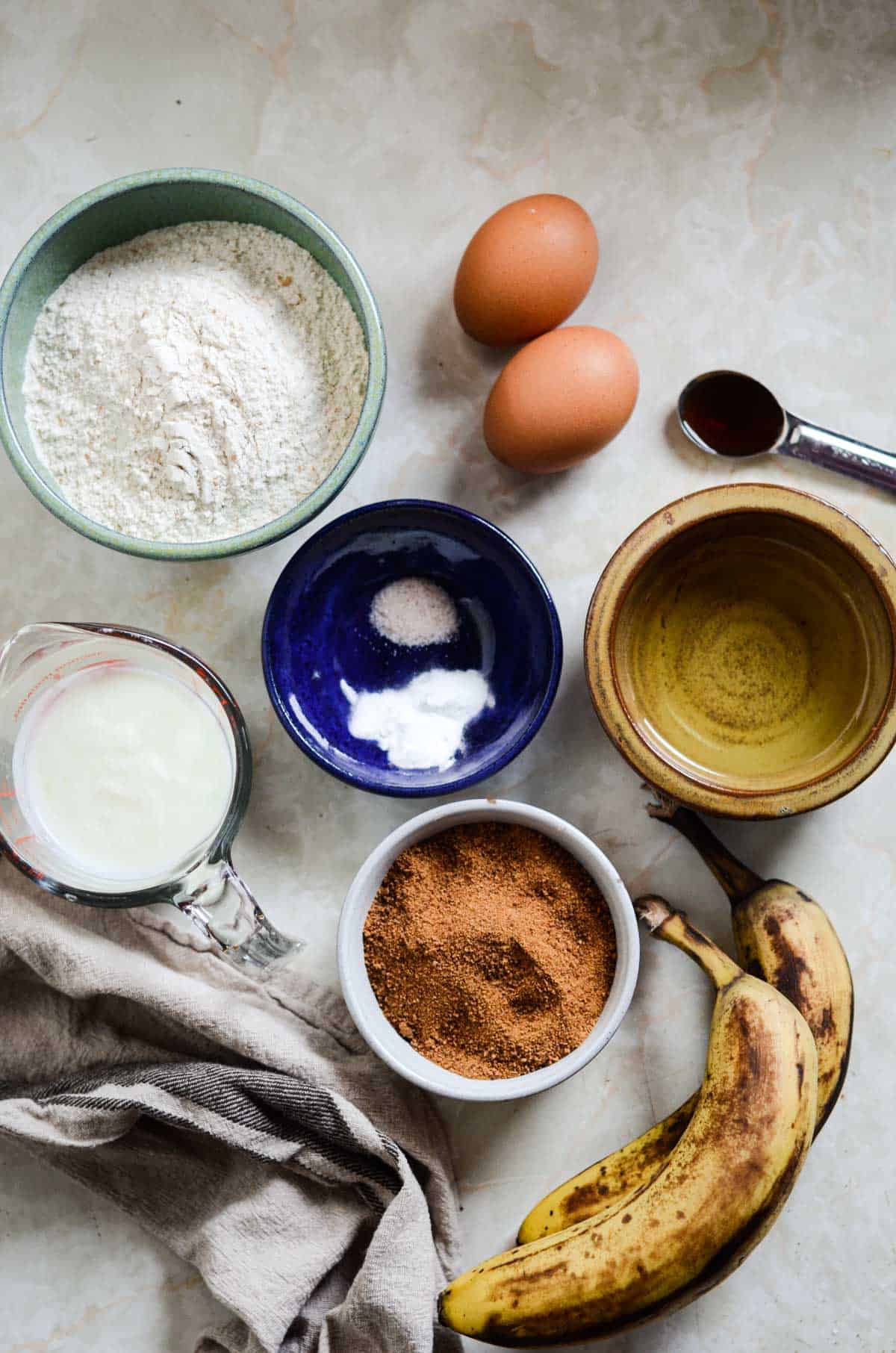 Flour, coconut sugar, baking soda, salt, eggs, oil, vanilla, bananas, yogurt, measuring into little bowls ready to make banana bread.