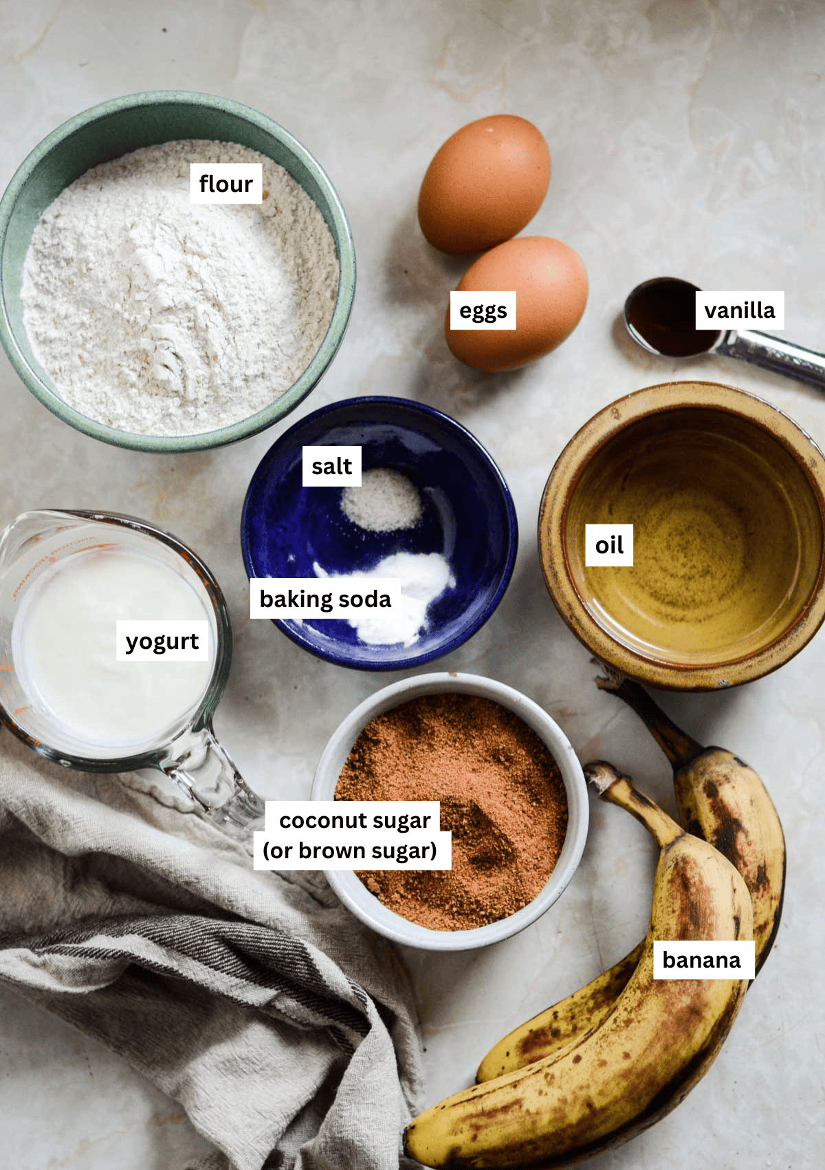 Flour, coconut sugar, baking soda, salt, eggs, oil, vanilla, bananas, yogurt, measuring into little bowls ready to make banana bread.
