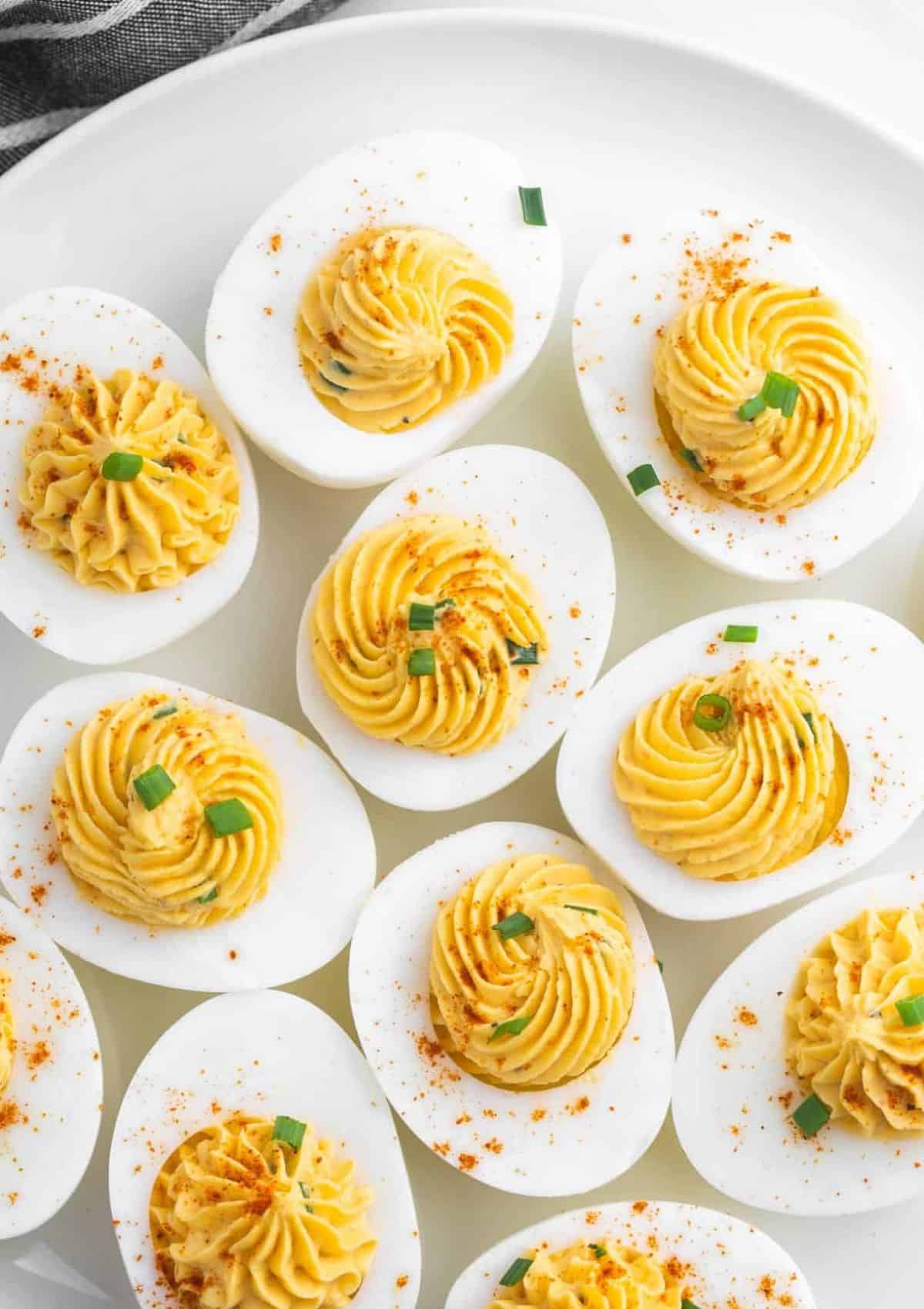 Sliced open boiled eggs with yellow egg yolk mixture inside eggs with paprika on top.