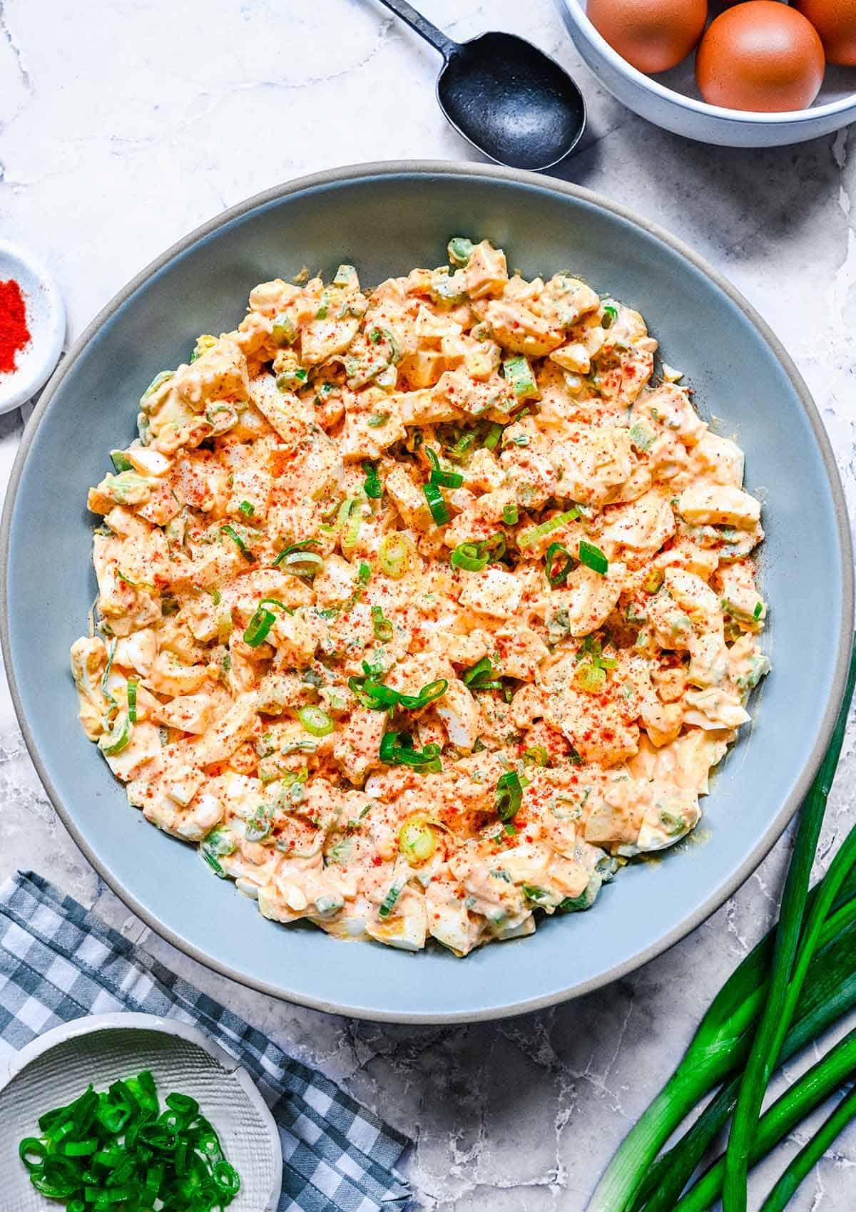 Chopped eggs in a bowl with a slightly red paprika sauce.