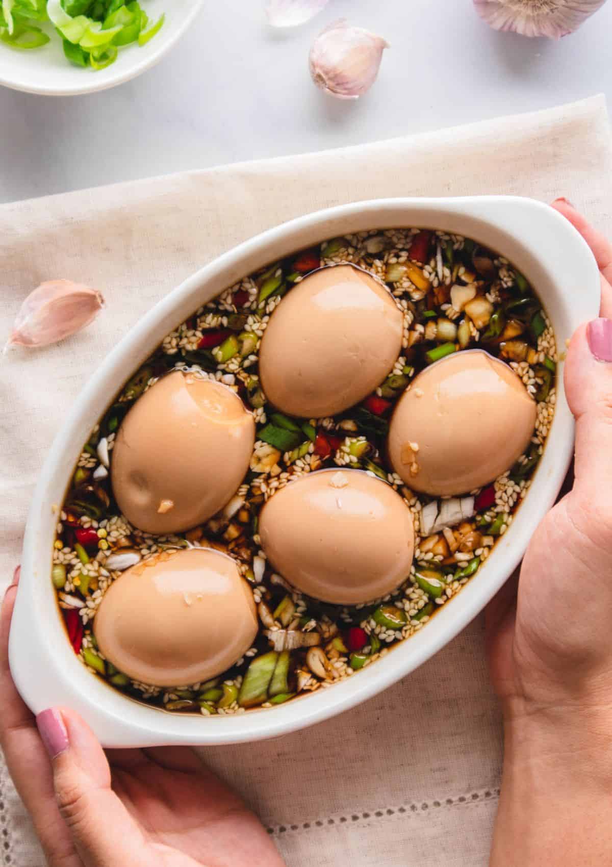 Boiled eggs marinating in a soy sauce base with chilies and green onions.